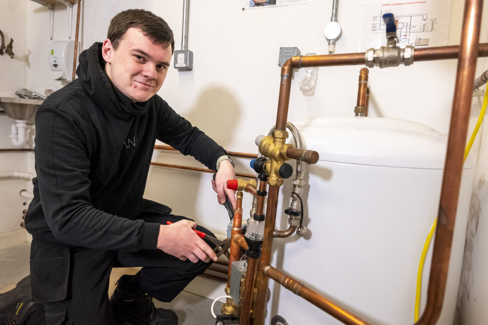 a plumbing student knelt working on pipes