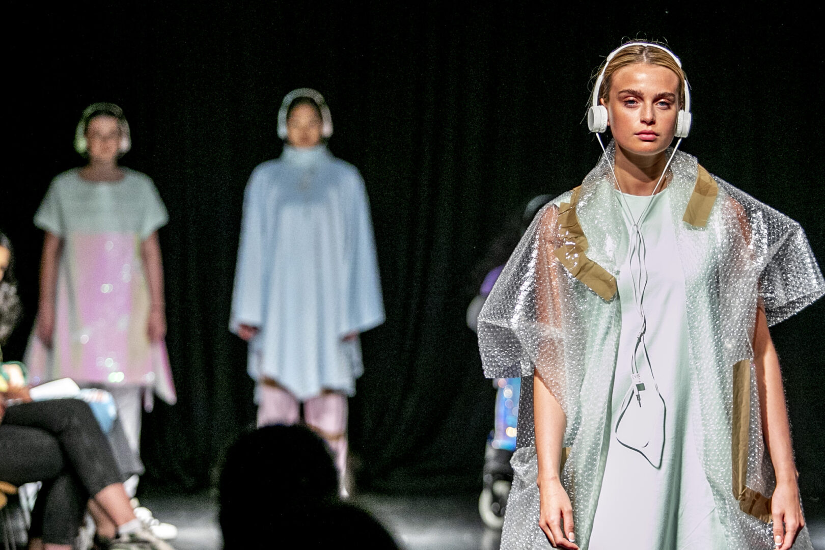 a fashion show model in the foreground on the runway